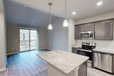 Located at 104 Breunig Blvd in Waunakee, WI, this well-appointed one-bedroom, one-bathroom unit offers a thoughtfully designed layout across a single floor. The open-concept kitchen and living area serves as the heart of the home, showcasing rich dark-toned cabinetry, a classic white subway tile backsplash, and a generous island with marble-look countertops illuminated by elegant pendant lighting. A full suite of stainless steel appliances completes the kitchen. Light wood-style flooring flows throughout the main living areas, enhancing the bright, airy atmosphere. Sliding glass doors lead to a private balcony, flooding the living space with natural light and offering views of the surrounding community. The bedroom features plush carpeting, a ceiling fan, and a large window that continues to invite natural light into the space. A dedicated closet provides convenient storage. The bathroom is finished with a matching dark vanity, marble-look countertop, and a tub-shower combination. A stacked in-unit washer and dryer adds everyday convenience. Clean lines, neutral tones, and modern finishes throughout create a cohesive and contemporary living environment.