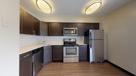 This thoughtfully designed 3-floor residence offers a cohesive blend of functionality and modern finishes throughout its multiple levels. The kitchen is a standout feature, showcasing rich dark-espresso shaker-style cabinetry, light countertops, and a classic white subway tile backsplash. A full suite of stainless steel appliances — including a refrigerator, range, over-the-range microwave, and dishwasher — completes the space, all set atop durable wood-look flooring. A central staircase with metal railings connects all three levels, providing an open sightline between floors. The main and upper levels feature carpeted bedrooms with neutral tones and ample natural light from well-placed windows. Bedrooms are equipped with built-in closets for generous storage. One full bathroom on the upper level features rich slate-toned tile flooring, a dark vanity, and a tub-shower combination. A second full bathroom on the lower level offers light ceramic tile flooring and a curved glass-door shower. The finished lower level provides additional versatile living space, benefiting from a skylight that brings in natural light. Throughout, the space maintains a clean, neutral palette, creating a calm and inviting atmosphere across all three floors.