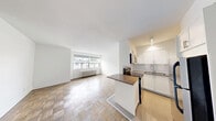 Located at 2175 Avenue Rd in Toronto's desirable Avenue Road corridor, this efficiently designed unit offers a thoughtful layout across a single floor. The combined kitchen and living area forms the heart of the space, where a parquet hardwood floor adds warmth and character throughout. Large windows flood the living area with natural light and offer views of the surrounding neighbourhood, complemented by a classic cast-iron radiator beneath the sill. The kitchen is neatly defined by a peninsula with a dark countertop, providing a functional transition between cooking and living zones. White shaker cabinetry, subway tile backsplash, stainless steel appliances — including a full-size refrigerator and range — and recessed lighting give the kitchen a clean, modern feel. The bathroom is finished with floor-to-ceiling white subway tile, a soaker tub with overhead shower, a compact modern vanity with chrome fixtures, and a multi-light vanity fixture above a large mirror, creating a bright and crisp atmosphere. Throughout the unit, crisp white walls and light-toned finishes contribute to an open, airy ambiance that maximizes the sense of space.