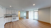This single-floor residence offers a clean, functional layout with a cohesive design aesthetic carried throughout each space. The open-concept kitchen and living area serves as the heart of the unit, where light wood-tone flooring extends seamlessly underfoot. The kitchen is outfitted with white cabinetry, speckled stone-finish countertops, a stainless steel sink, and white appliances including an electric range and over-the-range microwave. Recessed lighting illuminates the area, which flows naturally into a spacious living area bathed in natural light from a large floor-to-ceiling window dressed with vertical blinds that offer views of the surrounding greenery.

The bedrooms feature plush carpeting, ceiling fans, and generously sized windows with vertical blinds, providing both comfort and ample daylight. Two bathrooms are finished with marble-style tile flooring, white vanities with stone countertops, and full tub-shower combinations with brushed gold hardware accents. A dedicated laundry room houses a full-sized washer and dryer set, adding everyday convenience. Throughout, the unit maintains a bright, neutral palette that creates a welcoming and well-lit atmosphere.