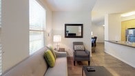 This well-appointed single-floor unit offers a thoughtfully designed layout that maximizes comfort and functionality across its one bedroom and one bathroom. The open-concept living and dining area is bathed in natural light from multiple windows fitted with horizontal blinds, creating a bright and welcoming atmosphere. The living room provides ample space for seating and entertainment, with wood-look flooring that flows seamlessly throughout the main areas. The dining space features direct access to an exterior door, adding convenience and a connection to the outdoors. The kitchen is outfitted with contemporary light wood cabinetry, gray countertops, a full suite of stainless steel appliances including a refrigerator, electric range, and over-the-range microwave, along with a clean tile backsplash that ties the design together. The bedroom is a serene retreat with multiple windows allowing natural light and garden views, neutral tones, and a spacious mirrored sliding-door closet offering generous storage. The bathroom includes a light wood vanity with a taupe countertop, large mirrors, and a separate shower area. A dedicated in-unit laundry closet with a stacked washer and dryer adds everyday practicality to this comfortable residence.