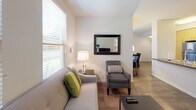 This well-appointed single-floor unit offers a thoughtfully designed layout that maximizes comfort and functionality across its one bedroom and one bathroom. The open-concept living and dining area is bathed in natural light from multiple windows fitted with horizontal blinds, creating a bright and welcoming atmosphere. The living room provides ample space for seating and entertainment, with wood-look flooring that flows seamlessly throughout the main areas. The dining space features direct access to an exterior door, adding convenience and a connection to the outdoors. The kitchen is outfitted with contemporary light wood cabinetry, gray countertops, a full suite of stainless steel appliances including a refrigerator, electric range, and over-the-range microwave, along with a clean tile backsplash that ties the design together. The bedroom is a serene retreat with multiple windows allowing natural light and garden views, neutral tones, and a spacious mirrored sliding-door closet offering generous storage. The bathroom includes a light wood vanity with a taupe countertop, large mirrors, and a separate shower area. A dedicated in-unit laundry closet with a stacked washer and dryer adds everyday practicality to this comfortable residence.
