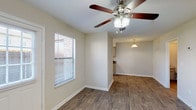 This two-story residence offers three bedrooms and two and a half bathrooms across a practical, well-organized floor plan. The main level features wood-style flooring throughout the living and dining areas, which are brightened by natural light from windows fitted with blinds. Ceiling fans are present in the living spaces, providing both function and visual interest. The living area flows openly toward the kitchen, which is equipped with ample cabinetry in a neutral finish, dark laminate countertops, a stainless steel sink, and white appliances including an electric range. A pendant light accents the transition between the kitchen and dining area. A half bathroom on the main level provides added convenience, featuring a vanity with storage and wood-style flooring. The staircase leads to the upper level, where the three bedrooms are located. Each bedroom features plush carpeting, a ceiling fan, and a window allowing natural light. The full bathrooms include vanities with cabinet storage, and one features a tiled walk-in shower. Neutral wall tones and clean white trim are consistent throughout, creating a cohesive and understated aesthetic across the entire home.