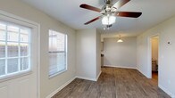 This two-story residence offers three bedrooms and two and a half bathrooms across a practical, well-organized floor plan. The main level features wood-style flooring throughout the living and dining areas, which are brightened by natural light from windows fitted with blinds. Ceiling fans are present in the living spaces, providing both function and visual interest. The living area flows openly toward the kitchen, which is equipped with ample cabinetry in a neutral finish, dark laminate countertops, a stainless steel sink, and white appliances including an electric range. A pendant light accents the transition between the kitchen and dining area. A half bathroom on the main level provides added convenience, featuring a vanity with storage and wood-style flooring. The staircase leads to the upper level, where the three bedrooms are located. Each bedroom features plush carpeting, a ceiling fan, and a window allowing natural light. The full bathrooms include vanities with cabinet storage, and one features a tiled walk-in shower. Neutral wall tones and clean white trim are consistent throughout, creating a cohesive and understated aesthetic across the entire home.