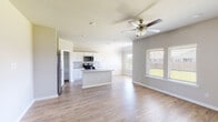 This single-story home offers a clean, modern layout designed for comfortable everyday living. The open-concept main area seamlessly connects the kitchen and living space, creating a bright and airy atmosphere enhanced by natural light from multiple windows fitted with blinds. Ceiling fans are present throughout, adding to the home's functional appeal.

The kitchen is a standout feature, equipped with crisp white shaker-style cabinetry, granite countertops, a subway tile backsplash, and a full suite of stainless steel appliances including a gas range, over-the-range microwave, refrigerator, and dishwasher. A central island provides additional prep space, while a dedicated walk-in pantry offers generous storage. Light wood-look flooring flows consistently throughout the main living areas and bedrooms, lending the home a cohesive and contemporary feel.

The bedrooms are generously proportioned, each featuring ceiling fans and ample natural light. The primary suite includes an en-suite bathroom with a soaking tub and shower combination, a toilet, and access to a walk-in closet. A second full bathroom mirrors this layout, featuring a tub/shower combo and granite-topped vanity. A hallway with overhead ventilation connects the private areas of the home. The spacious attached two-car garage with an automatic opener completes this well-appointed residence.