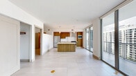 Located in the heart of Miami's Brickell neighborhood, this modern residence offers a thoughtfully designed single-floor layout with 1 bedroom, 2 bathrooms, and 2 closets. Large-format porcelain tile flooring flows throughout the entire unit, lending a clean, cohesive aesthetic to every room.

The open-concept living and dining area is bathed in natural light through floor-to-ceiling glass sliding doors that open to a private balcony with sweeping city views. A ceiling fan adds comfort to the spacious main living area.

The kitchen is a standout feature, showcasing warm wood-toned cabinetry, a white subway tile backsplash, a central island with a light quartz countertop, and a full suite of stainless steel appliances including a refrigerator, range with hood, built-in microwave, and dishwasher. Pendant lighting above the island adds a modern touch.

The primary bedroom is generously sized and includes direct balcony access through a sliding glass door, offering additional city views and natural light. Two closets provide ample storage throughout the unit.

Both bathrooms are finished with clean, modern materials, featuring wood-vanity cabinetry, white quartz countertops, illuminated mirrors, and tiled tub-shower combinations, maintaining a consistent, contemporary design language throughout the home.