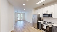 Located at 725–735 Coleman Blvd in Mount Pleasant, SC, this one-bedroom, one-bathroom residence offers a thoughtfully designed single-floor layout with a clean, modern aesthetic throughout. Light wood-tone flooring runs continuously across the living area, kitchen, bedroom, and hallway, creating a cohesive and airy feel.

The kitchen is a standout feature, showcasing a two-tone cabinetry design with crisp white upper cabinets and slate-blue lower cabinets, complemented by white quartz countertops and a classic subway tile backsplash. A full suite of stainless steel appliances — including a French door refrigerator with ice maker, a range, an over-the-range microwave, and a dishwasher — provides functionality and style. A skylight overhead adds natural brightness to this central space.

The open living area flows seamlessly from the kitchen, bathed in recessed lighting and natural light. The bedroom is a comfortable, well-proportioned retreat featuring two windows with views of surrounding greenery, a ceiling fan, and light-filled walls in a neutral palette. A hallway connects the main living areas to the full bathroom, which offers a tub/shower combination with white tile surround, oil-rubbed bronze fixtures, and light wood flooring that carries through from the rest of the unit. The overall ambiance is bright, clean, and move-in ready.