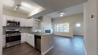 Located in Atlanta, GA, this single-floor residence offers a thoughtfully designed open-concept layout that seamlessly connects the kitchen, dining, and living areas. The kitchen is outfitted with white shaker-style cabinetry, granite countertops, a tile backsplash, and a full suite of stainless steel appliances including a gas range, built-in microwave, refrigerator, and dishwasher. A peninsula provides additional workspace and casual seating while overlooking the main living area.

The living room is a standout space, anchored by a classic fireplace with a white mantle and flanked by built-in shelving and cabinetry. A large picture window floods the room with natural light and offers views of the surrounding greenery, while vaulted ceilings lend a sense of openness and volume.

Rich, dark hardwood-style flooring runs throughout the main living areas, while the bedroom features plush carpeting and a ceiling fan for added comfort. The bathroom is finished with granite countertops, white cabinetry, and hardwood-style flooring, maintaining the cohesive design aesthetic found throughout the home. A dedicated laundry closet with a full-size washer and dryer adds a practical, convenient touch to this well-appointed Atlanta residence.