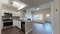 Located in Atlanta, GA, this single-floor residence offers a thoughtfully designed open-concept layout that seamlessly connects the kitchen, dining, and living areas. The kitchen is outfitted with white shaker-style cabinetry, granite countertops, a tile backsplash, and a full suite of stainless steel appliances including a gas range, built-in microwave, refrigerator, and dishwasher. A peninsula provides additional workspace and casual seating while overlooking the main living area.

The living room is a standout space, anchored by a classic fireplace with a white mantle and flanked by built-in shelving and cabinetry. A large picture window floods the room with natural light and offers views of the surrounding greenery, while vaulted ceilings lend a sense of openness and volume.

Rich, dark hardwood-style flooring runs throughout the main living areas, while the bedroom features plush carpeting and a ceiling fan for added comfort. The bathroom is finished with granite countertops, white cabinetry, and hardwood-style flooring, maintaining the cohesive design aesthetic found throughout the home. A dedicated laundry closet with a full-size washer and dryer adds a practical, convenient touch to this well-appointed Atlanta residence.