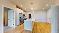 This 1,010-square-foot single-story home in Mount Pleasant, WI offers 2 bedrooms, 2 bathrooms, and a well-designed layout with modern finishes throughout. The kitchen is a standout feature, showcasing white shaker-style upper cabinets, gray lower cabinets, and a large center island with a white quartz countertop and matte black faucet. Stainless steel appliances, including a refrigerator with ice maker, electric range, microwave, and dishwasher, complete the space, which flows over light hardwood-style flooring accented by pendant lighting. Both bathrooms feature white quartz vanity tops, gray cabinetry, matte black hardware, and light wood-look flooring, with one bathroom offering a tub/shower combo. The primary bedroom measures 190 square feet and includes a dedicated closet with wire shelving. The second bedroom is carpeted and benefits from a large window with natural light. Two closets and a stacked in-unit washer and dryer add practical storage and convenience. The attached garage features a concrete floor and automatic opener. Neutral tones and clean lines give the home a cohesive, contemporary aesthetic throughout.