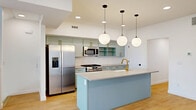Located at 11 Merrimac Ave in Salt Lake City, UT, this contemporary multi-story townhome offers a well-designed layout spread across four floors. The ground level features an attached garage with ample space, while the main living floor hosts an open-concept kitchen, dining, and living area. The kitchen is a standout feature, showcasing sage-green cabinetry with gold hardware, a large center island with a quartz countertop, a gold-finish faucet, subway tile backsplash, stainless steel appliances, and globe pendant lighting — all set over warm-toned hardwood flooring. The bright, airy bedrooms feature large windows that invite natural light and offer views of the surrounding neighborhood, complemented by clean white walls and the same warm hardwood floors. The primary bedroom is generously sized and connects to a well-appointed en-suite bathroom with dual vanities, sage cabinetry with gold hardware, a glass-enclosed shower, and matte black fixtures. A total of four bathrooms serve the residence, with dedicated closets, a laundry area, a pantry, and a utility room rounding out the functional spaces. The crowning feature is a rooftop patio offering sweeping views of the Wasatch Mountains and the Salt Lake City skyline — an exceptional outdoor retreat above the city.