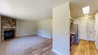 This single-floor unit offers a well-organized layout with a clear distinction between living and functional spaces. The kitchen is equipped with stainless steel appliances, including a full-size refrigerator, electric range, and over-the-range microwave. Warm-toned cabinetry pairs with light granite-style countertops, providing a clean and functional cooking area. Wood-look flooring runs through the kitchen and entry areas, transitioning to soft, neutral carpet in the living and bedroom spaces.

The living area is generously proportioned and bathed in natural light from multiple large multi-pane windows and a glass-paneled exterior door, offering views of surrounding greenery. A ceiling fan with a light fixture adds functionality to the space. The textured popcorn ceilings are consistent throughout, giving the unit a cohesive feel.

The bedrooms are carpeted and well-sized, with neutral walls, ample floor space, and natural light from exterior windows. One bedroom features a sliding double-door closet. The bathroom includes a full tub and shower combination with clean white surrounds, wood-look tile flooring, and a vanity with matching granite-style countertops. Overall, the unit presents a practical and comfortable living environment with updated finishes throughout.