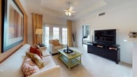 This single-floor residence offers a thoughtfully designed layout that balances comfort and functionality throughout. The living room serves as the heart of the home, featuring a tray ceiling with a ceiling fan, plush carpeting, and French doors that flood the space with natural light and provide access to an outdoor area. Bold accent walls in warm terracotta and sage green tones lend each room a distinct character and visual warmth.

The galley-style kitchen is efficiently organized with light wood cabinetry, white countertops, a double-basin sink, and white appliances including a dishwasher and refrigerator. Adjacent to the kitchen, the dining area accommodates a round table beneath a pendant light fixture, accented by a large wall mirror that enhances the sense of space.

The bedrooms are generously sized, each featuring soft carpeting, large windows with serene outdoor views — including a picturesque waterfront scene — and ample closet space, including mirrored sliding closet doors in one room. One bedroom benefits from a connected bathroom and walk-in closet.

Both bathrooms are finished with tile flooring, white vanity cabinetry, and soaking tubs with shower combinations. The overall ambiance is warm and inviting, with cohesive design choices that create a comfortable, livable environment throughout.