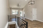 This thoughtfully designed two-story home offers a comfortable and functional layout across two main floors and an unfinished basement. The main level welcomes you with a dedicated entrance and soaring ceilings in the living area, accented by warm light hardwood flooring, recessed lighting, and a stylish geometric pendant chandelier. The galley-style kitchen is a standout feature, boasting white shaker cabinetry, granite countertops, stainless steel appliances, a subway tile backsplash, and a walk-in pantry — all set atop hardwood floors.

The upper floor is home to both bedrooms, two full bathrooms, and multiple closets. The primary bedroom suite includes a well-appointed en-suite bathroom with dual granite vanities, white cabinetry, brushed nickel fixtures, a glass-enclosed shower, and direct access to a spacious walk-in closet with wire shelving. The secondary bedroom features plush carpet, vaulted ceilings, and a bright window. A staircase with a sleek metal railing connects the floors, flanked by hallways that provide excellent flow. The unfinished basement offers generous open space with exposed joists and a concrete floor, presenting strong potential for future customization.
