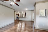 Located at 17802 Mound Rd in Houston, TX, this single-story, 3-bedroom, 2-bathroom home offers a well-designed open-concept layout finished with rich hardwood-style flooring throughout. The welcoming entrance leads into a bright, airy living room featuring crown molding, a ceiling fan, and abundant natural light filtering through blinds-covered windows. The space flows seamlessly into the dining area and kitchen, where dark espresso cabinetry, a granite-topped peninsula island, stainless steel appliances, a tile backsplash, and stylish pendant lighting create a functional yet refined hub for the home. A dedicated pantry provides added storage convenience. The spacious primary bedroom features a ceiling fan and connects to a well-appointed walk-in closet outfitted with wire shelving systems. The bathrooms are finished with dark wood vanities and wood-look flooring; one includes a glass-enclosed tiled walk-in shower. Two additional bedrooms offer versatile living options. An in-unit laundry room accommodates a full-size washer and dryer. The attached garage provides secure parking and extra storage. With seven closets distributed throughout, this home delivers exceptional storage capacity alongside a clean, neutral aesthetic throughout.