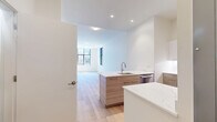 Located in Boston's vibrant 02215 corridor, this modern one-bedroom, one-bathroom unit offers a thoughtfully designed layout filled with natural light and contemporary finishes throughout. Light-toned hardwood flooring runs continuously across the entire space, lending warmth and visual cohesion to every room.

The open living area is bright and airy, anchored by large black-framed windows that frame views of the surrounding urban streetscape. The kitchen is a standout feature, equipped with stainless steel GE appliances including a range, over-the-range microwave, refrigerator, and dishwasher. Two-tone cabinetry pairs light wood lower cabinets with crisp white uppers, complemented by a white tile backsplash and quartz countertops with an undermount sink.

The bedroom is generously proportioned, featuring dual black-framed windows that flood the room with natural light and offer views of the neighborhood. A built-in closet with sliding doors provides ample storage.

The bathroom is finished in a clean, neutral palette with large-format tile flooring, a wood-toned vanity with white quartz countertop, and a glass-enclosed walk-in shower with textured tile surround. Recessed lighting completes the polished aesthetic of this well-appointed Boston residence.