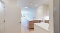 Located in Boston's vibrant 02215 corridor, this modern one-bedroom, one-bathroom unit offers a thoughtfully designed layout filled with natural light and contemporary finishes throughout. Light-toned hardwood flooring runs continuously across the entire space, lending warmth and visual cohesion to every room.

The open living area is bright and airy, anchored by large black-framed windows that frame views of the surrounding urban streetscape. The kitchen is a standout feature, equipped with stainless steel GE appliances including a range, over-the-range microwave, refrigerator, and dishwasher. Two-tone cabinetry pairs light wood lower cabinets with crisp white uppers, complemented by a white tile backsplash and quartz countertops with an undermount sink.

The bedroom is generously proportioned, featuring dual black-framed windows that flood the room with natural light and offer views of the neighborhood. A built-in closet with sliding doors provides ample storage.

The bathroom is finished in a clean, neutral palette with large-format tile flooring, a wood-toned vanity with white quartz countertop, and a glass-enclosed walk-in shower with textured tile surround. Recessed lighting completes the polished aesthetic of this well-appointed Boston residence.