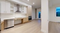 Located at 2826 Jacklin Rd in Victoria, BC, this thoughtfully designed 2-bedroom, 1-bathroom unit offers a clean, modern aesthetic with light-toned hardwood flooring and crisp white walls throughout. The open-concept living, dining, and kitchen area serves as the heart of the home, featuring a well-appointed kitchen with two-tone cabinetry in white and natural wood, a marble-look tile backsplash, stainless steel appliances including a built-in wall oven and refrigerator, a sleek cooktop with a stainless steel range hood, and recessed lighting. A wall-mounted mini-split unit provides efficient climate control in the living area. The two bedrooms are bright and simply finished, each with light flooring and windows that bring in natural light and outdoor views. Three closets provide generous storage throughout the unit. The accessible bathroom is spaciously laid out, equipped with grab bars, a roll-in glass-enclosed shower, and a floating vanity. In-unit laundry adds everyday convenience. A private balcony with glass railings offers elevated views of the surrounding Victoria neighbourhood and distant water. A connecting hallway ties all spaces together in a functional, streamlined layout ideal for comfortable everyday living.