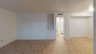 This single-story space offers a practical and functional layout across several well-defined areas. The living room is generously sized, featuring tile flooring with a stone-like pattern, white walls, and a wide window that allows natural light to fill the room. A built-in shelving unit with lower cabinet storage adds a convenient and classic architectural detail to the space.

The kitchen is compact and efficient, outfitted with white cabinetry, light-toned countertops, a white drop-in sink, and a white electric range. Wood-look flooring and a small window provide a clean, bright atmosphere. Adjacent areas connect seamlessly through a hallway.

The bedrooms are carpeted and feature ceiling fans with integrated light fixtures, providing comfort and airflow. Windows dressed with horizontal blinds invite natural light while offering privacy. One bedroom features a distinctive rounded wall detail, adding subtle architectural character.

Both bathrooms are finished in crisp white, with tiled tub-and-shower surrounds, vanity cabinets with light countertops, large mirrors, and bright vanity lighting. One bathroom features wood-look flooring, while the other is finished in tile. The overall aesthetic throughout the space is clean, neutral, and move-in ready.
