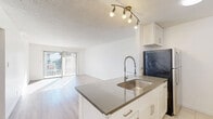 Located at 1601 N Poinsettia Pl in Los Angeles, CA 90046, this 1-bedroom, 2-bathroom residence offers a well-designed, single-floor layout that maximizes every square foot with a clean, modern aesthetic throughout.

The open-concept living and dining area is bright and airy, featuring light hardwood-style flooring and a sliding glass door that leads directly to a private balcony, flooding the space with natural light. The kitchen is a standout feature, outfitted with white shaker cabinetry, stainless steel appliances including an electric range and refrigerator, a dark tile backsplash, and a peninsula with a grey quartz countertop and a professional-style coil faucet — ideal for both everyday cooking and entertaining.

The spacious primary bedroom includes a sliding glass door with access to an outdoor view and generous closet space among the four closets found throughout the unit. Both bathrooms are finished with tile flooring and neutral toned tile work; one features a glass-enclosed walk-in shower with mosaic tile flooring, while the other includes a tiled shower enclosure with warm-toned wall tile.

With a neutral white palette, track lighting in the kitchen, and ample storage, this residence offers a functional and contemporary living experience in a prime Los Angeles location.