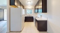 Located at 4598 N 39th St in the vibrant North Park neighborhood of San Diego, this single-floor unit offers a thoughtfully updated interior with a clean, modern aesthetic throughout. The open living area greets you with fresh light wood-style flooring, crisp white walls, and a ceiling fan that enhances airflow and comfort. Natural light filters in through a window, creating a bright and welcoming atmosphere. The space flows seamlessly into the kitchen and dining area, where a transition to light-toned tile flooring marks the change in zones. The galley-style kitchen is well-appointed with rich dark cabinetry providing ample upper and lower storage, white quartz-style countertops, a stainless steel microwave, a freestanding range, and a full-size refrigerator. A window above the sink brings in natural light, making the kitchen feel open and functional. The bathroom is finished with a matching dark vanity topped with a white countertop and an integrated sink, a large wall mirror with overhead lighting, tile flooring, a full shower, and a window for natural ventilation. Grab bars are also present, adding accessibility. Overall, this unit presents a cohesive, updated living environment well-suited to everyday comfort in a prime San Diego location.