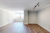 Located in the heart of Midtown Atlanta at 1270 W Peachtree St NW, this three-bedroom, two-bathroom residence offers a well-organized single-floor layout designed for comfortable urban living. The spacious living room features rich, dark hardwood-style flooring, crown molding, and track lighting, with large floor-to-ceiling windows that flood the space with natural light and frame sweeping city skyline views. A pass-through window connects the living area to the kitchen, which features light wood cabinetry and dark granite countertops, creating an open and connected feel. Both bathrooms are finished with dark granite vanity countertops, rich wood cabinetry, and framed mirrors. The full bathroom includes a tiled tub-and-shower surround with neutral stone-toned tiles for a clean, modern aesthetic. The three bedrooms are carpeted for comfort, each offering generous proportions and large windows with views of the Atlanta skyline, allowing ample natural light throughout. The primary bedroom provides a notably spacious retreat. Two hallways guide circulation throughout the unit, contributing to a logical and practical flow. Neutral gray tones across the walls complement the flooring and finishes, giving the entire space a cohesive, contemporary look suited to Midtown Atlanta living.