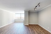 Located in the heart of Midtown Atlanta at 1270 W Peachtree St NW, this three-bedroom, two-bathroom residence offers a well-organized single-floor layout designed for comfortable urban living. The spacious living room features rich, dark hardwood-style flooring, crown molding, and track lighting, with large floor-to-ceiling windows that flood the space with natural light and frame sweeping city skyline views. A pass-through window connects the living area to the kitchen, which features light wood cabinetry and dark granite countertops, creating an open and connected feel. Both bathrooms are finished with dark granite vanity countertops, rich wood cabinetry, and framed mirrors. The full bathroom includes a tiled tub-and-shower surround with neutral stone-toned tiles for a clean, modern aesthetic. The three bedrooms are carpeted for comfort, each offering generous proportions and large windows with views of the Atlanta skyline, allowing ample natural light throughout. The primary bedroom provides a notably spacious retreat. Two hallways guide circulation throughout the unit, contributing to a logical and practical flow. Neutral gray tones across the walls complement the flooring and finishes, giving the entire space a cohesive, contemporary look suited to Midtown Atlanta living.