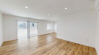 Located at 1185 Myra Ave in Los Angeles, this thoughtfully updated 2-bedroom, 2-bathroom residence offers a clean, modern aesthetic throughout its single-floor layout. Warm, light-toned hardwood-style flooring runs continuously across the living areas, complemented by crisp white walls and recessed lighting that keep the space feeling bright and open.

The spacious living area features a sliding glass door with vertical blinds that opens onto a private balcony, allowing natural light to pour in. A wall-mounted mini-split system provides efficient climate control in both the living area and bedrooms. The galley-style kitchen is well-appointed with white shaker cabinetry, quartz countertops, a subway tile backsplash, black matte hardware, a stainless steel undermount sink, dishwasher, gas range, and overhead microwave.

Both bedrooms are comfortably sized, each equipped with individual mini-split HVAC units and windows with natural views. The primary bedroom offers a generous footprint. A dedicated closet and stacked in-unit laundry add everyday practicality. The bathrooms are stylishly finished, highlighted by a walk-in glass shower with white subway tile, hexagonal slate-toned floor tile, a wall-mounted sink, and black matte fixtures. A separate dining area completes the well-organized floor plan.