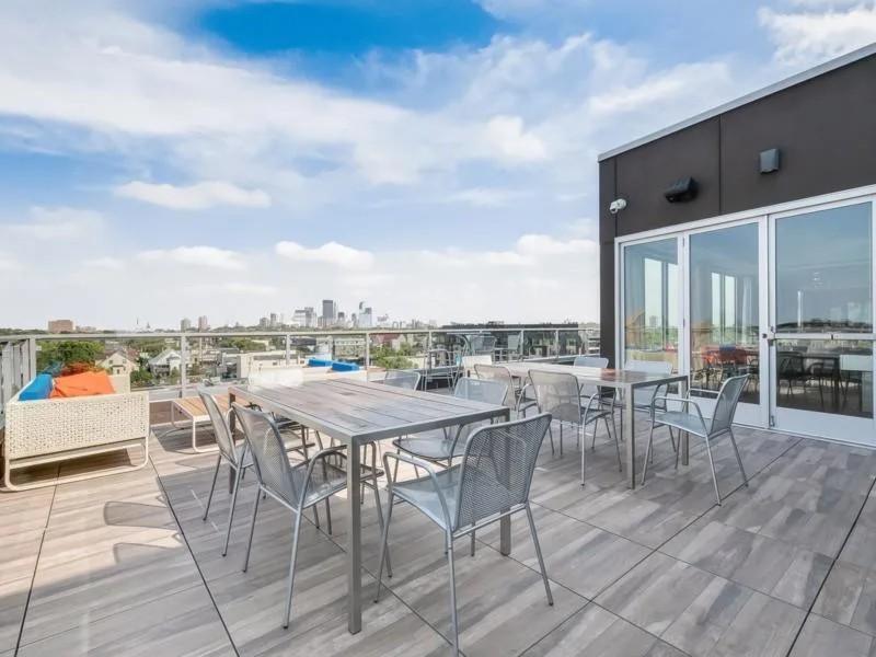 Rooftop patio with tables and chairs overlooking city skyline.