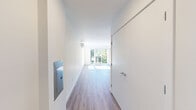 Located at 4221 37th Ave S in Seattle's vibrant Columbia City neighborhood, this thoughtfully designed one-bedroom, one-bathroom residence offers a bright and contemporary living experience across a generously sized single floor. The open-concept layout is anchored by a sun-drenched living room featuring large sliding glass doors that flood the space with natural light and provide direct access to a spacious private balcony. The balcony offers sweeping views of the surrounding tree-lined neighborhood and serves as an ideal outdoor retreat. Wide-plank hardwood-style flooring runs throughout, lending warmth and cohesion to every room. The kitchen is efficiently positioned along the corridor, outfitted with stainless steel appliances and modern cabinetry. The bedroom is a tranquil retreat with a sliding closet and its own access to the balcony, complemented by an additional dedicated closet for ample storage. The full bathroom is sleekly appointed with a long white vanity, a large mirror, and in-unit stacked washer and dryer. A wall-mounted mini-split system provides year-round climate control. Clean white walls, recessed lighting, and a crisp modern aesthetic define the overall ambiance of this well-appointed urban residence.