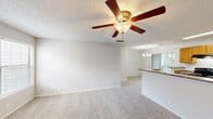 This well-appointed one-bedroom, one-bathroom residence in Birmingham, Alabama offers a comfortable and functional single-floor layout. The open-concept living, dining, and kitchen area creates a seamless flow, anchored by plush wall-to-wall carpeting and neutral tones throughout. A standout feature of the living room is the tile-surround fireplace with a classic white mantel, complemented by a ceiling fan with a light fixture and windows that allow natural light to fill the space. The galley-style kitchen is equipped with warm wood cabinetry, granite-look countertops, black appliances including a range and refrigerator, a double-basin sink, and durable hardwood-style flooring. A pass-through counter connects the kitchen to the dining area, which is accented by an elegant chandelier. The spacious bedroom features carpeting, a ceiling fan, and a window with outdoor views. The full bathroom includes a tiled tub/shower combo, toilet, and a large mirror. Additional highlights include two closets for ample storage, a dedicated laundry area, and a textured ceiling throughout. This residence offers a practical and inviting layout suited for everyday living.