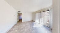 This single-floor unit offers a clean, functional layout designed for comfortable everyday living. The main living area is bright and open, featuring light wood-style flooring and large sliding glass doors dressed with vertical blinds that invite abundant natural light and provide access to an outdoor area. A standard entry door sits adjacent to the sliding doors, offering convenient street-level access. The living space flows into a galley-style kitchen outfitted with warm honey-toned cabinetry, speckled laminate countertops, a double-coil electric range, a built-in dishwasher, a refrigerator, and an overhead microwave — all finished in white for a cohesive look. Wood-style flooring continues throughout the kitchen. The bedrooms are carpeted with neutral tones, offering a softer underfoot feel, and each room benefits from windows with vertical blinds that filter natural light. The bathroom features a full tub and shower combo with white subway tile surround, wood-look vinyl flooring, a toilet, and a vanity with warm wood cabinetry and light countertops. Throughout the unit, a consistent neutral color palette, textured ceilings, and overhead ventilation contribute to a tidy, move-in-ready atmosphere.