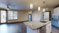 Located at 14900 Memorial Dr in Houston's Memorial area, this well-appointed 2-bedroom, 2-bathroom residence offers a thoughtfully designed single-level floor plan. The open-concept kitchen and living area serves as the heart of the home, showcasing dark hardwood-style flooring, white cabinetry, stainless steel appliances, a tile backsplash, and a large granite-topped island with pendant lighting overhead — ideal for both cooking and entertaining. The living area flows naturally toward a private balcony with metal railings, offering views of the surrounding community. The primary bedroom features hardwood-style flooring, large windows that invite natural light, and a ceiling fan, while the second bedroom offers plush carpeting, a ceiling fan, and its own window. Both bedrooms are supported by dedicated closets with built-in shelving and hanging rods for ample storage. The primary bathroom is well-appointed with granite countertops, a soaking tub, a separate glass-enclosed shower, and tile flooring. A dedicated laundry room with built-in shelving adds everyday convenience. Neutral tones and consistent finishes throughout give the space a cohesive, modern aesthetic.