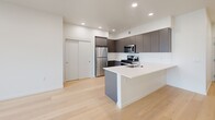 Located at 3956 N Vancouver Ave in Portland's vibrant North Williams corridor, this modern one-bedroom, one-bathroom unit offers a thoughtfully designed layout with contemporary finishes throughout. Light-toned hardwood floors extend across the open living area, creating a warm and cohesive aesthetic.

The kitchen is a standout feature, equipped with full-height matte gray cabinetry, stainless steel appliances including a gas range, microwave, and refrigerator, and a white quartz peninsula with an integrated sink — ideal for both cooking and casual dining. Recessed lighting illuminates the space efficiently.

The bedroom is a bright, comfortable retreat featuring large floor-to-ceiling windows that invite natural light and offer views of the surrounding Portland neighborhood. A dedicated closet provides practical storage.

The bathroom is finished in a clean, minimalist style with light tile flooring, a modern floating vanity with a white countertop, sleek gray cabinetry, and a backlit mirror that adds a refined touch.

A private balcony with glass railings extends the living space outdoors, offering open views of the Portland cityscape. The unit also includes a closet off the main living area, adding further storage convenience. The overall design balances modern urban living with functional, well-appointed spaces.