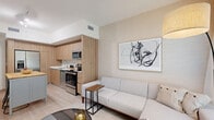 Located at 15955 NW 6th Avenue in Miami, FL, this thoughtfully designed one-bedroom, one-bathroom unit offers a cohesive modern aesthetic defined by warm, natural tones and clean lines throughout. The open-concept layout seamlessly connects the living room and kitchen, creating an efficient yet inviting flow. The living area features textured grasscloth-style wallcovering, light wood flooring, and sheer floor-to-ceiling curtains that invite abundant natural light. A framed abstract art piece anchors the main wall, adding a contemporary artistic touch. The kitchen is outfitted with flat-front wood-toned cabinetry, stainless steel appliances including a French door refrigerator, over-the-range microwave, and range, complemented by a crisp white countertop and a functional kitchen island. The bedroom is a calm retreat with soft, neutral wallcovering, sheer window treatments, and a stylish sliding barn door that connects to the bathroom. The bathroom features a full tub-shower combination with white tile surround, a wood-vanity with a white countertop, and clean white walls throughout. A dedicated closet provides additional storage. The overall ambiance is warm, minimalist, and modern, making excellent use of every inch of the space.