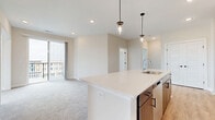 Located in Mason, Ohio, this thoughtfully designed 2-bedroom, 2-bathroom residence offers a well-appointed single-level layout with a generous, flowing floor plan. The open-concept kitchen and living area serves as the heart of the home, anchored by a large white quartz island with a built-in sink and pendant lighting overhead. The kitchen features rich wood-toned cabinetry, a white subway tile backsplash, and stainless steel appliances, including a refrigerator, range, and microwave. Light wood-style flooring grounds the kitchen, which transitions seamlessly into plush carpeted living and bedroom areas.

The spacious living room connects to an outdoor balcony through sliding glass doors, bringing in natural light and views of the vibrant District Park neighborhood. The generously sized primary bedroom offers large windows with community views, direct balcony access, and a dedicated walk-in closet with built-in wire shelving. The primary bathroom features light wood-style flooring, a dual-sink vanity with contrasting blue cabinetry, and a walk-in shower. A second bedroom includes a ceiling fan and broad windows. Additional highlights include a versatile den, four closets total, and a clean, neutral palette throughout that creates a bright and cohesive ambiance.