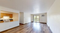 Located at 31 Olympic Village in Chicago Heights, IL, this single-floor residence offers three bedrooms, two bathrooms, and a well-organized layout designed for comfortable living. The open-concept living room is a standout feature, with gleaming hardwood-style flooring that flows throughout the space, crisp white walls, and a wall-unit air conditioner. Sliding glass doors lead to a private balcony, filling the room with natural light and providing pleasant outdoor views. A pass-through window connects the living area to the kitchen, which features warm wood cabinetry, dark countertops, a double sink, and white appliances including a refrigerator, dishwasher, and range. The three bedrooms are bright and functional, each with hardwood-style flooring, generous closet space with louvered bi-fold doors, and large windows that bring in natural light. The primary bedroom is a comfortable size with ample storage. The two bathrooms are finished with wood-toned vanities, light countertops, and large mirrors; one includes a sliding-door shower enclosure. A hallway connects the private rooms, and four closets throughout provide excellent storage. The overall ambiance is clean, bright, and move-in ready.
