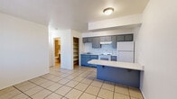 Located at 3802 N Flowing Wells Rd in Tucson, Arizona, this one-bedroom, one-bathroom unit offers a practical and efficient single-floor layout. Light-toned ceramic tile flooring runs throughout the entire space, creating a cohesive and easy-to-maintain interior.

The combined kitchen and living area serves as the heart of the home. The kitchen is equipped with two-tone cabinetry — gray upper cabinets and blue lower cabinets — paired with speckled countertops, a white electric range, a full-size refrigerator, and a single-basin sink. A blue kitchen peninsula provides additional counter space and doubles as a casual dining or workspace. An open built-in shelving unit adjacent to the kitchen offers convenient pantry storage.

The bedroom is a comfortable, well-defined space featuring a wall-unit air conditioner and a window fitted with vertical blinds, allowing for natural light and ventilation. A reach-in closet with a hanging rod provides practical storage.

The bathroom is neatly appointed with tile-surround tub and shower combination, a speckled vanity countertop with an integrated sink, a large mirror, and matching blue cabinetry consistent with the kitchen aesthetic. The layout is efficient and clean throughout.