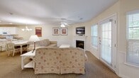 Located at 203 Fairway Dr in Clarkesville, GA, this well-appointed 2-bedroom, 4-bathroom single-floor residence offers a comfortable and functional layout with a warm, welcoming ambiance throughout. Warm cream-toned walls, carpeted living areas, and tile flooring in wet areas establish a cohesive aesthetic.

The open-concept living and dining area is anchored by a white fireplace with a wall-mounted TV above, ceiling fan, and access to the outdoors via a glass-panel door that fills the space with natural light. The adjacent dining area features a classic white chandelier above a white dining table with seating for six. The full kitchen is outfitted with white cabinetry, a breakfast bar with barstool seating, tile flooring, and white appliances including a refrigerator, range, and built-in microwave. A secondary kitchenette provides additional convenience.

The generously sized primary bedroom includes a ceiling fan, large windows, a sitting area, and a private en-suite bathroom featuring a dual-sink vanity, a soaking tub, and a separate shower. The second bedroom is well-proportioned with its own en-suite and direct entry access. Three additional bathrooms serve the residence, each finished with tile flooring and bright, clean fixtures.