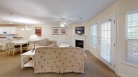 Located at 203 Fairway Dr in Clarkesville, GA, this well-appointed 2-bedroom, 4-bathroom single-floor residence offers a comfortable and functional layout with a warm, welcoming ambiance throughout. Warm cream-toned walls, carpeted living areas, and tile flooring in wet areas establish a cohesive aesthetic.

The open-concept living and dining area is anchored by a white fireplace with a wall-mounted TV above, ceiling fan, and access to the outdoors via a glass-panel door that fills the space with natural light. The adjacent dining area features a classic white chandelier above a white dining table with seating for six. The full kitchen is outfitted with white cabinetry, a breakfast bar with barstool seating, tile flooring, and white appliances including a refrigerator, range, and built-in microwave. A secondary kitchenette provides additional convenience.

The generously sized primary bedroom includes a ceiling fan, large windows, a sitting area, and a private en-suite bathroom featuring a dual-sink vanity, a soaking tub, and a separate shower. The second bedroom is well-proportioned with its own en-suite and direct entry access. Three additional bathrooms serve the residence, each finished with tile flooring and bright, clean fixtures.
