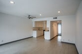 Located at 126 E 18th St in Costa Mesa, California, this single-story unit offers a clean, functional layout with bright, neutral finishes throughout. The open living and dining area features light wood-style flooring, recessed lighting, a ceiling fan, and a sliding glass door fitted with vertical blinds that allows natural light to flow in. A wall-mounted air conditioning unit provides climate control, and a secondary sliding glass door connects to an adjacent space, enhancing the sense of openness.

The galley-style kitchen is well-appointed with crisp white cabinetry, light countertops, a double-basin stainless steel sink, and stainless steel appliances including a gas range, built-in microwave, and dishwasher. Recessed lighting illuminates the workspace, while light wood-style flooring continues underfoot. A peninsula counter separates the kitchen from the living area, providing additional prep or serving space.

The bedrooms are carpeted for comfort and each features a large sliding glass door with vertical blinds, inviting generous natural light and providing outdoor access. The bathroom is finished in a clean, minimalist style with light wood-style flooring, a full tub/shower combination with a curved curtain rod, a white vanity with storage, and a mirror. The overall palette of whites and light neutrals throughout the unit creates a bright, airy ambiance.