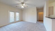 Located at 5577 Houston Rd in Macon, Georgia, this 1-bedroom, 1-bathroom unit is designed for comfortable, efficient single-floor living. The living room is generously sized, featuring plush wall-to-wall carpeting, crown molding, a ceiling fan with light fixture, and a front entry door with access to a private outdoor deck. Natural light filters in through blinds-covered windows and a set of French doors, creating a bright and welcoming atmosphere. A half-wall peninsula connects the living area to the kitchen, which features wood-look vinyl flooring, light wood cabinetry, dark granite-style countertops, and black appliances including a refrigerator, range, and dishwasher. Ample cabinet and pantry storage adds to the kitchen's practicality. The bedroom is a well-proportioned, carpeted retreat with a ceiling fan, a large window for natural light, and access to a walk-in closet. The full bathroom is cleanly finished with wood-look flooring, a tub/shower combination with tile surround, a wooden vanity with a stone-style countertop, and a large mirror. Throughout the unit, neutral tones and textured ceilings maintain a consistent, understated aesthetic suited to a variety of décor styles.