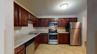 Located at 55 Golfview Dr in Manchester, New Hampshire, this single-floor residence offers a well-appointed and functional layout designed for comfortable everyday living. The kitchen is a standout feature, showcasing rich dark cherry cabinetry, granite-look countertops, and a full suite of stainless steel appliances including a gas range, over-the-range microwave, refrigerator, and dishwasher. Light tile flooring completes the kitchen's clean, practical aesthetic. The open living area is generously sized, featuring wall-to-wall carpeting, baseboard heating, and a sliding glass door that fills the room with natural light and provides access to an outdoor area with views of surrounding greenery. The layout connects the living space directly to the kitchen, creating an open, cohesive feel. The bedroom is well-proportioned, also finished with soft carpeting, and includes a built-in closet for storage. A full bathroom features a combined tub and shower, a vanity with an integrated sink, tile flooring, and clean neutral finishes throughout. Textured ceilings are consistent across the unit, contributing to its classic residential character. Overall, the space offers a practical and comfortable environment in a convenient Manchester location.