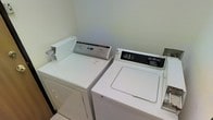 The laundry room is a compact, functional space designed to accommodate all washing and drying needs. It features a Whirlpool top-loading washing machine and a GE top-loading dryer, positioned side by side for ease of use. The room is finished with clean, light-colored walls that contribute to a bright and tidy atmosphere. The tile flooring adds a practical, easy-to-clean surface suited to the demands of a laundry space. Both appliances are full-sized, providing ample capacity for handling household laundry efficiently. The straightforward layout maximizes the use of the available space while keeping the machines accessible. Having dedicated laundry appliances on the main floor eliminates the need for shared or off-site laundry facilities, adding a layer of convenience and privacy. The room's no-frills design keeps the focus on utility, making it a reliable and efficient area for day-to-day laundry tasks.