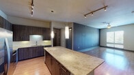 This 2-bedroom, 2-bathroom residence in Spring, Texas offers a well-designed single-story layout with contemporary finishes throughout. The open-concept kitchen serves as a central hub, showcasing a large granite-topped island with pendant lighting overhead, dark wood cabinetry extending to the ceiling, a white subway tile backsplash, and a full suite of stainless steel appliances including a refrigerator, range, and built-in microwave. Track lighting adds additional illumination to the space, which flows seamlessly into a spacious living area featuring wood-style flooring and a bold accent wall.

Both bedrooms are comfortably sized, featuring plush carpeting, ceiling fans, and windows with blinds that invite natural light and outdoor views. The primary bathroom is notably well-appointed, offering a dual-sink vanity with granite countertops, dark cabinetry, and framed mirrors, with a walk-in closet visible nearby. The secondary bathroom includes a granite-topped single vanity, a combined tub and shower, and wood-style flooring. A dedicated laundry area with an in-unit washer and dryer completes this thoughtfully designed residence.