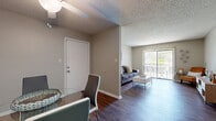 This single-floor, 2-bedroom, 1-bathroom residence offers a practical and comfortable layout designed to maximize its living space. The combined living and dining area serves as the heart of the home, featuring warm wood-look flooring, a textured ceiling, and a ceiling fan overhead. The dining area comfortably accommodates a round table for four, while the living room opens directly onto a private balcony through a full-width sliding glass door framed by vertical blinds, bringing in generous natural light and outdoor views of surrounding greenery.

The galley-style kitchen is efficiently organized with wood-toned cabinetry on both sides, ample counter space, a double-coil electric range, a dishwasher, and a full-size refrigerator. It connects conveniently to the laundry area. The bathroom features a full-size tub and shower combination, a floating wood-accented vanity with a light countertop, and wood-look flooring.

The primary bedroom includes a dedicated closet area with built-in shelving and rod storage, with direct access to the bathroom. The second bedroom is carpeted with a natural light-filled window and its own closet. Three closets throughout the unit provide additional storage. The space maintains a neutral, cohesive color palette throughout, creating a clean and inviting atmosphere.