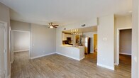 This single-floor residence offers a clean, modern design with a cohesive open-concept layout and wood-look flooring that flows seamlessly throughout. The living area is generously sized, bathed in natural light from multiple windows, and equipped with ceiling fans for added comfort. A sliding glass door provides direct outdoor access, enhancing the bright and airy atmosphere of the space.

The kitchen is thoughtfully designed with white cabinetry, a gray tile backsplash, stainless steel appliances — including a refrigerator, range, and over-the-range microwave — and a peninsula counter that opens toward the living area, making it ideal for both cooking and entertaining.

The bedroom is well-proportioned with natural light from a window and direct access to a spacious walk-in closet outfitted with built-in wire shelving and hanging rods, offering ample storage.

The primary bathroom features a wide dual-sink vanity with a white countertop, modern vessel-style sinks, sleek cabinetry, and large mirrors with overhead lighting. A secondary bathroom includes a shower-tub combination and clean, minimalist finishes. The entire unit maintains a neutral, contemporary palette that creates a calm and functional living environment.