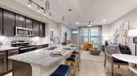 Located at 907 South Rd in Baytown, Texas, this single-floor residence offers a thoughtfully designed open-concept layout that seamlessly connects the kitchen, dining, and living areas. The kitchen is a standout feature, showcasing rich dark-espresso cabinetry, a classic white subway tile backsplash, granite countertops, stainless steel appliances, and a large center island with bar seating — ideal for both cooking and casual dining. Elegant pendant lighting and track lighting overhead add a refined finishing touch. Light-toned hardwood-style flooring flows throughout the main living spaces, enhancing the bright and airy ambiance created by multiple large windows with blinds. The living area is generously proportioned, with a ceiling fan, ample natural light, and space for a dedicated sitting or study nook. The bedrooms feature plush carpeting and large windows dressed with sheer curtains and blinds, creating a calm, restful atmosphere. One bedroom includes a spacious walk-in closet with extensive wire shelving and hanging systems. The neutral color palette throughout the home lends a clean, contemporary feel, making every room feel open, functional, and welcoming.