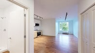 Located at 4240 Chestnut Street in Philadelphia's University City neighborhood, this efficiently designed single-floor unit offers a clean, modern aesthetic throughout. The open-concept layout maximizes the available space, with warm hardwood-style flooring and crisp white walls creating a bright, welcoming atmosphere. Sleek black track lighting runs the length of the main living area, providing ample illumination and a contemporary touch.

The kitchen is thoughtfully appointed with stainless steel appliances — including a gas range, microwave, dishwasher, and full-size refrigerator — paired with two-tone cabinetry featuring light wood lower cabinets and white upper cabinets, all set against a clean white countertop. A window at the far end of the living area allows natural light to flow in, offering a view of surrounding greenery.

The bathroom is neatly finished with a single-sink vanity with gray countertop and light wood cabinetry, a walk-in shower with white tile surround, and matching hardwood-style flooring that ties the space together cohesively. Throughout the unit, the design emphasizes clean lines, neutral tones, and functional simplicity, making it a well-organized and modern living space in a prime Philadelphia location.