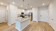 Located along Grand Oaks Blvd in Burlington, NC, this single-floor residence offers a thoughtfully designed layout with a clean, modern aesthetic throughout. The open-concept living and dining area is anchored by durable wood-look flooring, ceiling fans, and abundant natural light streaming through large windows and elegant French doors that lead to the outdoors. The kitchen is a standout feature, showcasing crisp white shaker-style cabinetry, granite countertops, a center island with a built-in sink and pendant lighting, and a full suite of stainless steel appliances including a range, over-the-range microwave, and refrigerator. The bedrooms offer plush carpeting and ample natural light, with one room featuring a ceiling fan for added comfort. Storage is well addressed with a spacious walk-in closet equipped with dual-level wire shelving. The bathroom is finished to a high standard, featuring a double-sink vanity with granite countertops, white cabinetry with brushed nickel hardware, a large mirror, and a combination tub and shower. Neutral tones and consistent finishes throughout lend the space a cohesive, move-in-ready appeal.